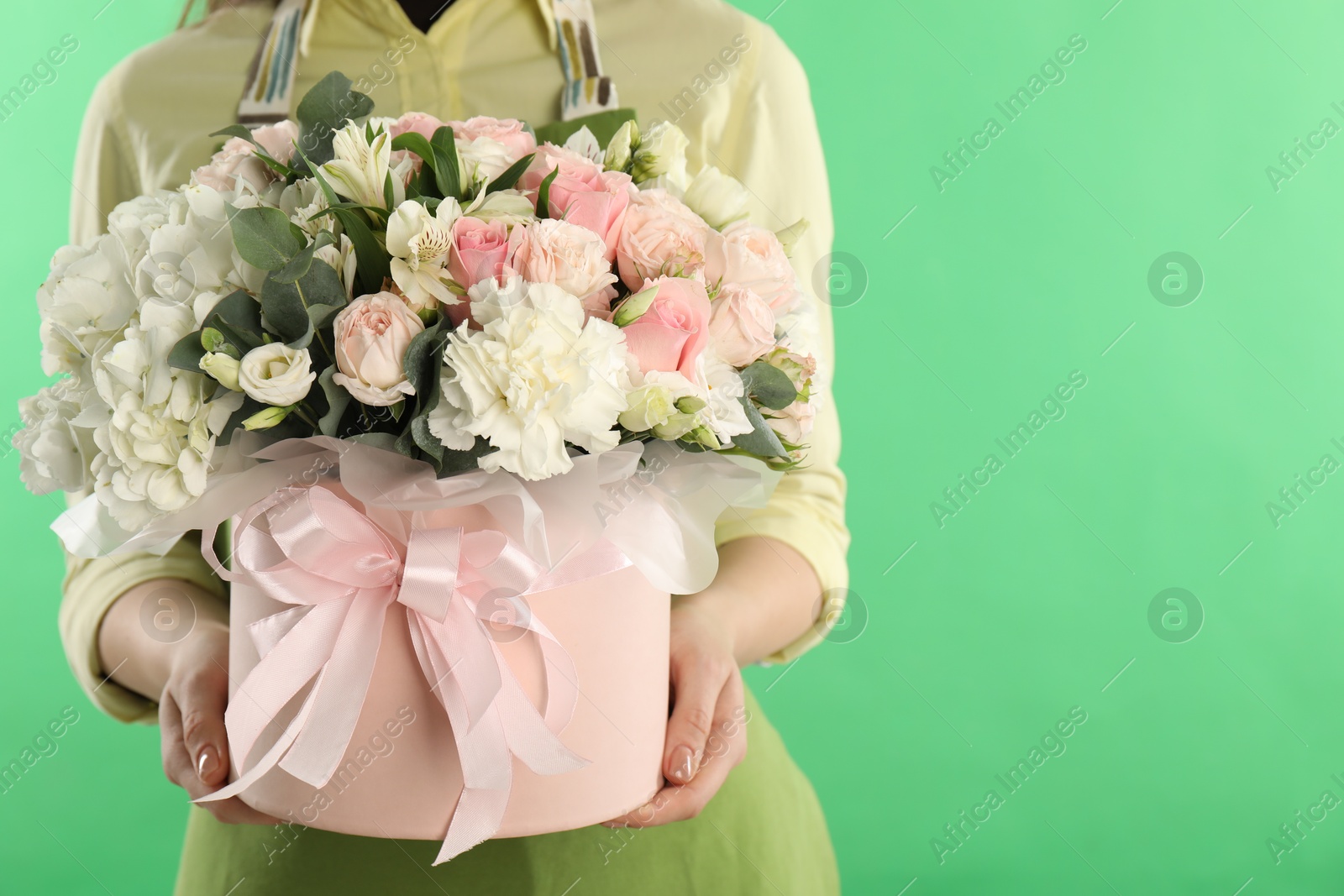 Photo of Florist with beautiful bouquet in box on green background, closeup. Space for text