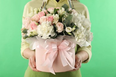 Photo of Florist with beautiful bouquet in box on green background, closeup