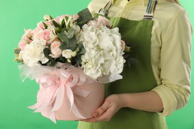 Photo of Florist with beautiful bouquet in box on green background, closeup