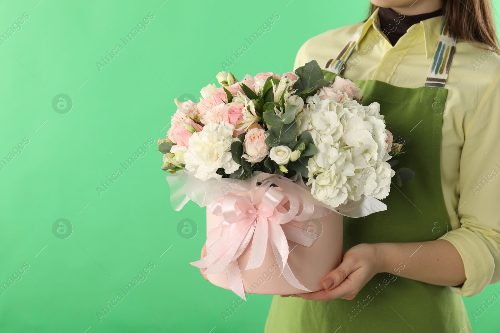 Photo of Florist with beautiful bouquet in box on green background, closeup. Space for text