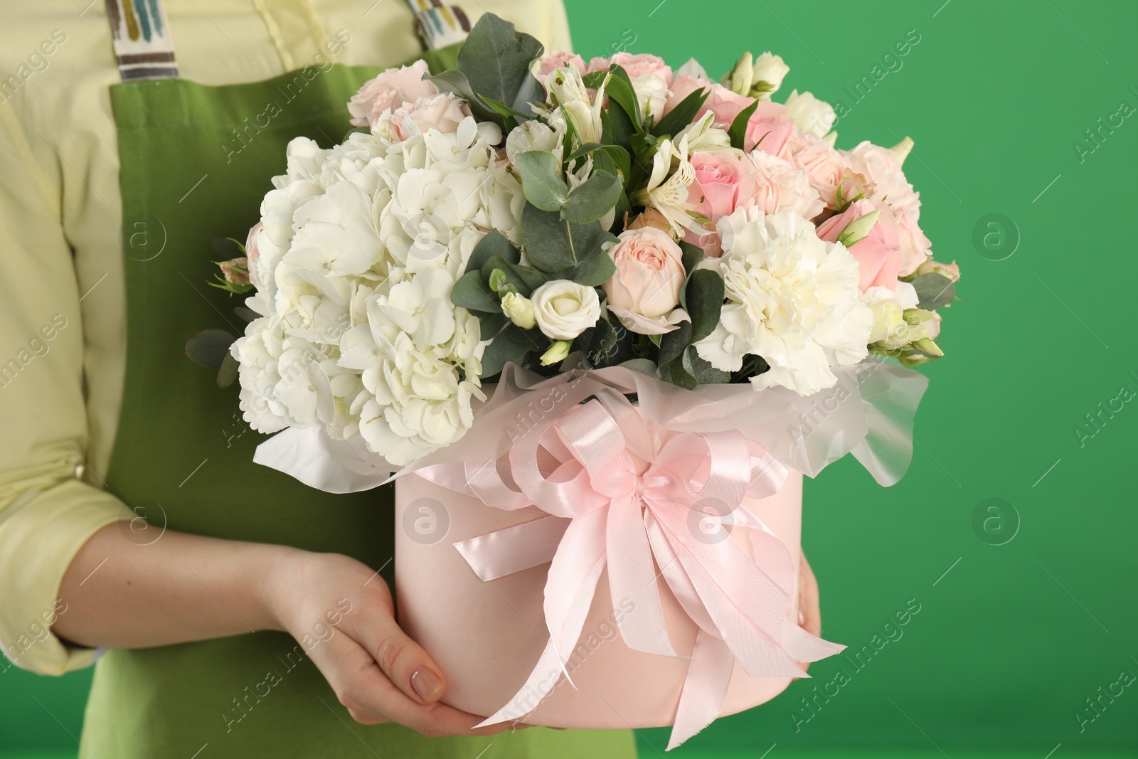 Photo of Florist with beautiful bouquet in box on green background, closeup