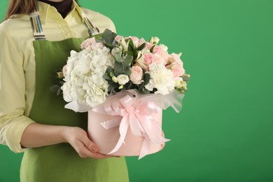 Photo of Florist with beautiful bouquet in box on green background, closeup. Space for text