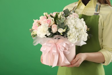 Photo of Florist with beautiful bouquet in box on green background, closeup. Space for text