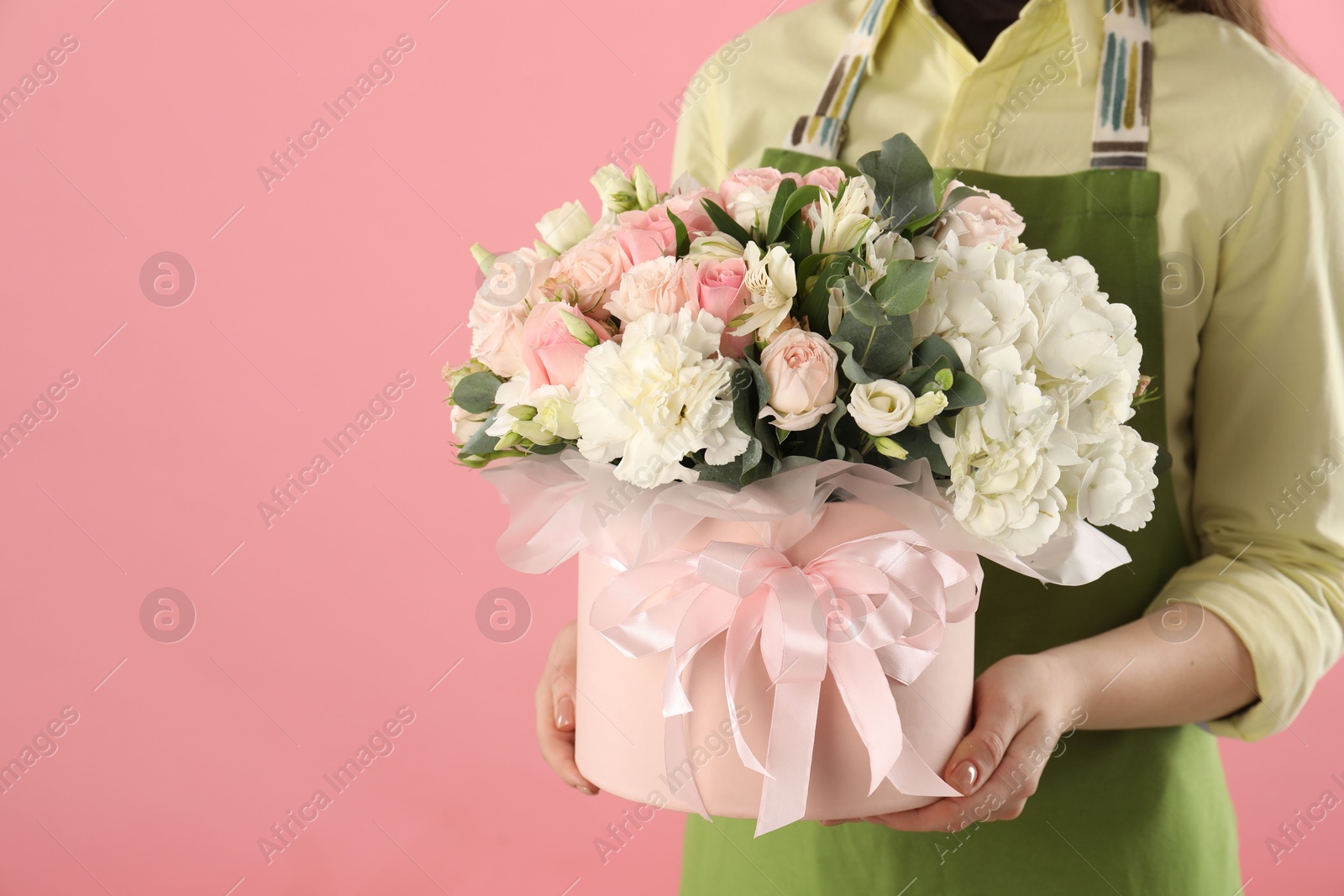 Photo of Florist with beautiful bouquet in box on pink background, closeup. Space for text