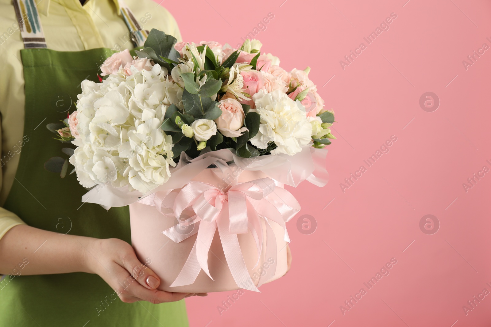 Photo of Florist with beautiful bouquet in box on pink background, closeup. Space for text