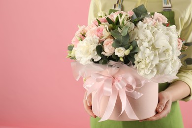 Photo of Florist with beautiful bouquet in box on pink background, closeup. Space for text