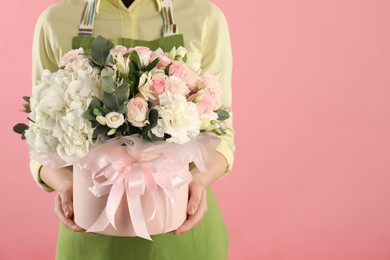 Photo of Florist with beautiful bouquet in box on pink background, closeup. Space for text