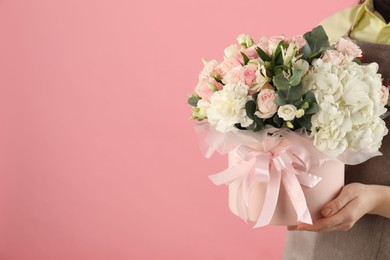 Photo of Florist with beautiful bouquet in box on pink background, closeup. Space for text