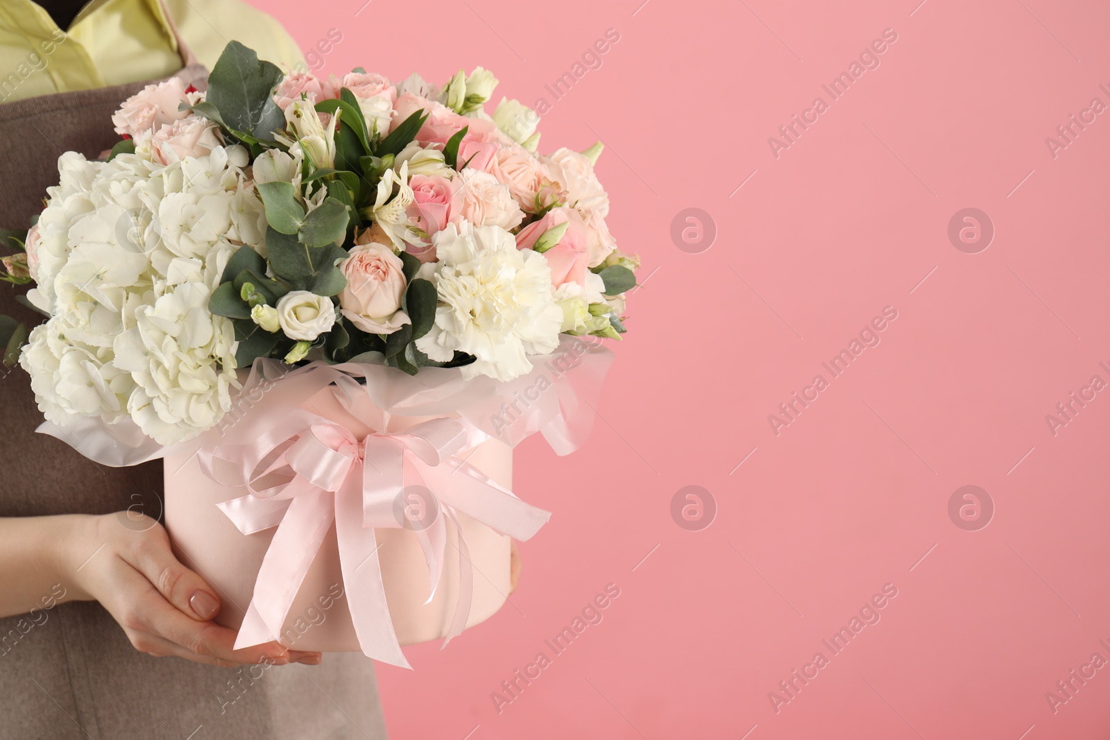 Photo of Florist with beautiful bouquet in box on pink background, closeup. Space for text