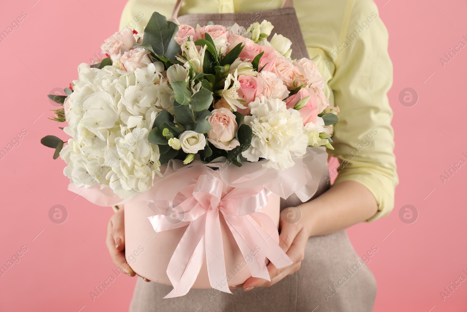 Photo of Florist with beautiful bouquet in box on pink background, closeup