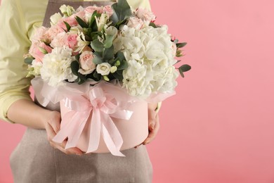 Photo of Florist with beautiful bouquet in box on pink background, closeup. Space for text