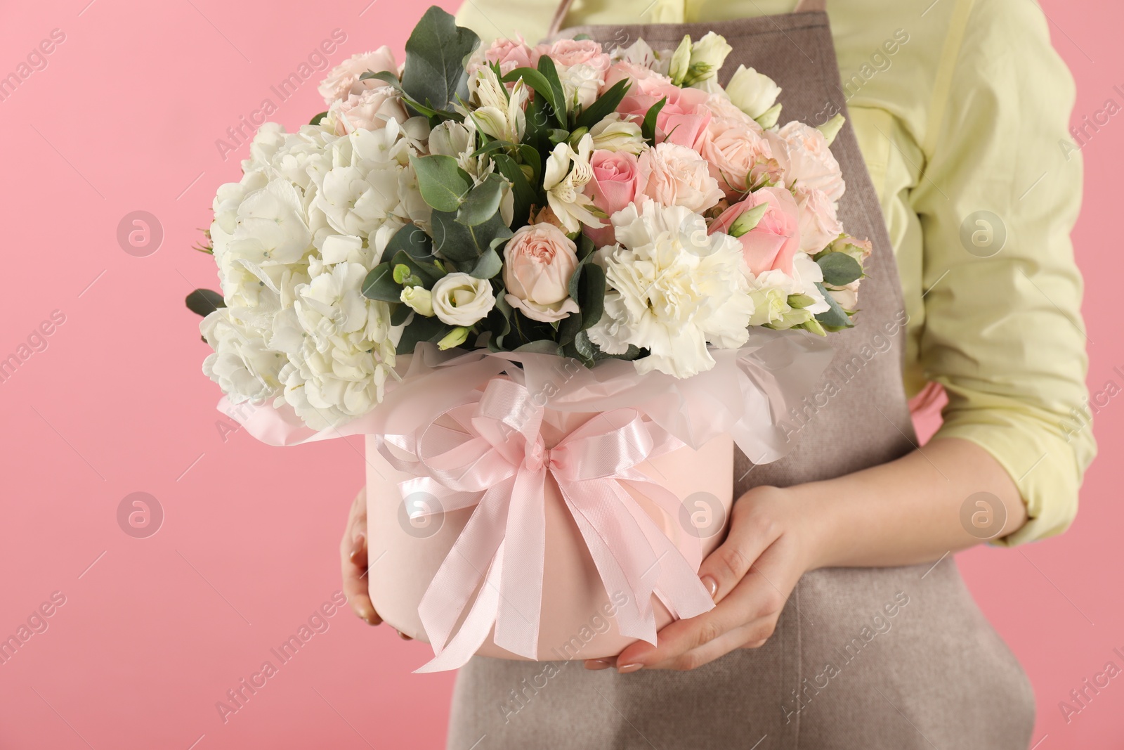 Photo of Florist with beautiful bouquet in box on pink background, closeup