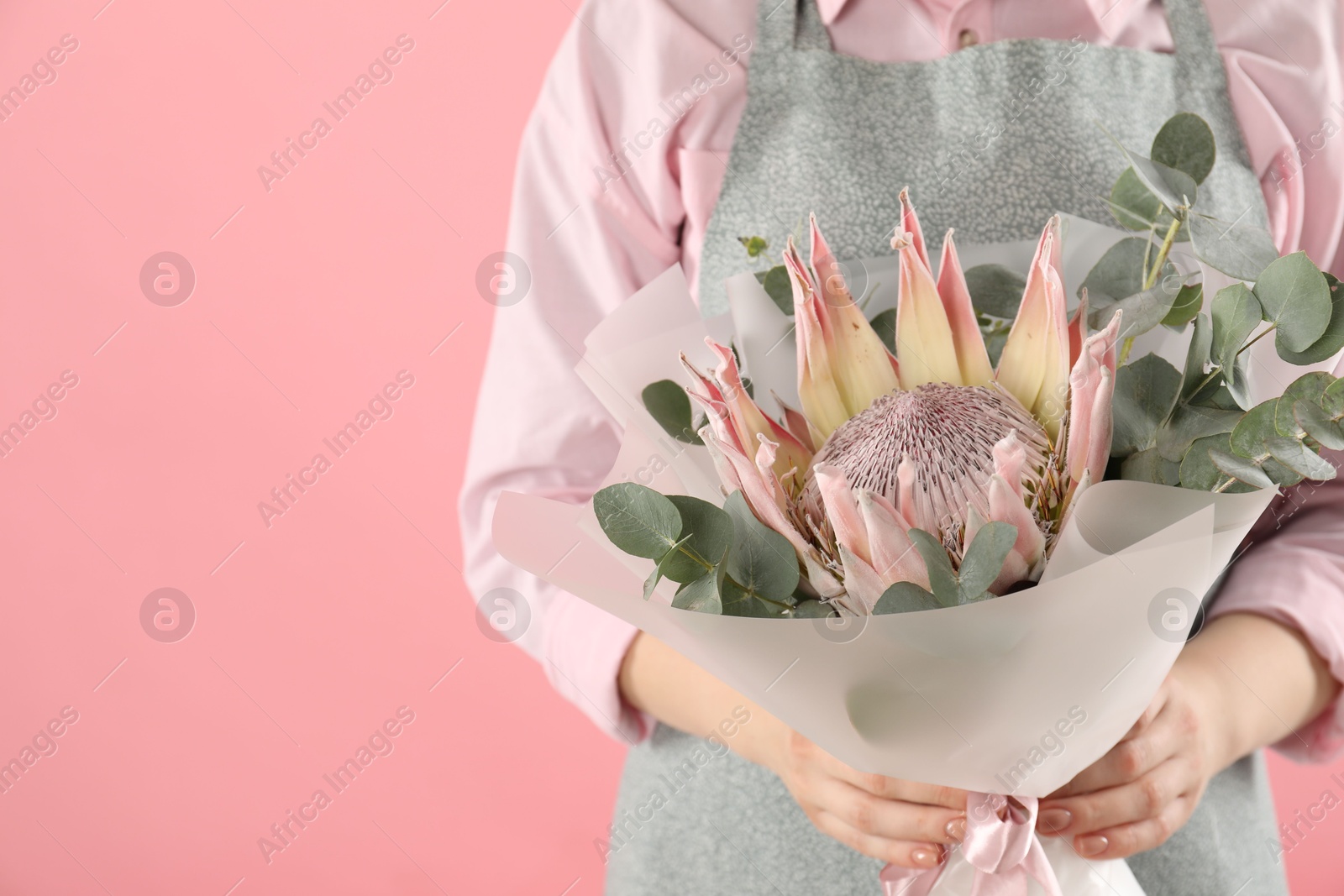 Photo of Florist with beautiful bouquet on pink background, closeup. Space for text