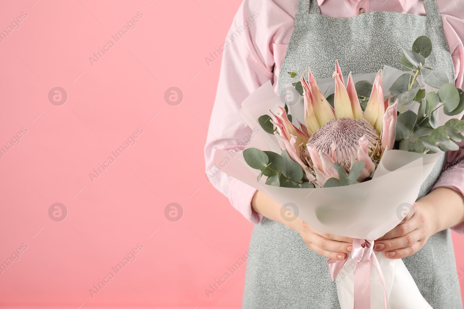 Photo of Florist with beautiful bouquet on pink background, closeup. Space for text