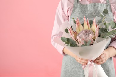 Photo of Florist with beautiful bouquet on pink background, closeup. Space for text