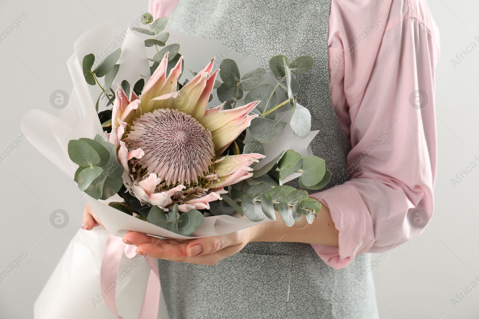 Photo of Florist with beautiful bouquet on light background, closeup