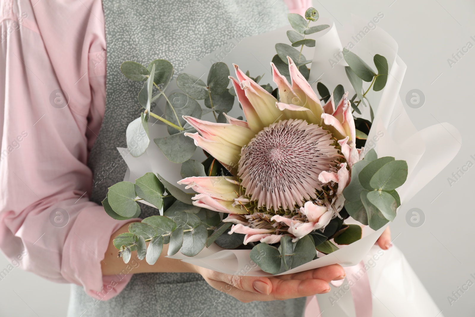 Photo of Florist with beautiful bouquet on light background, closeup