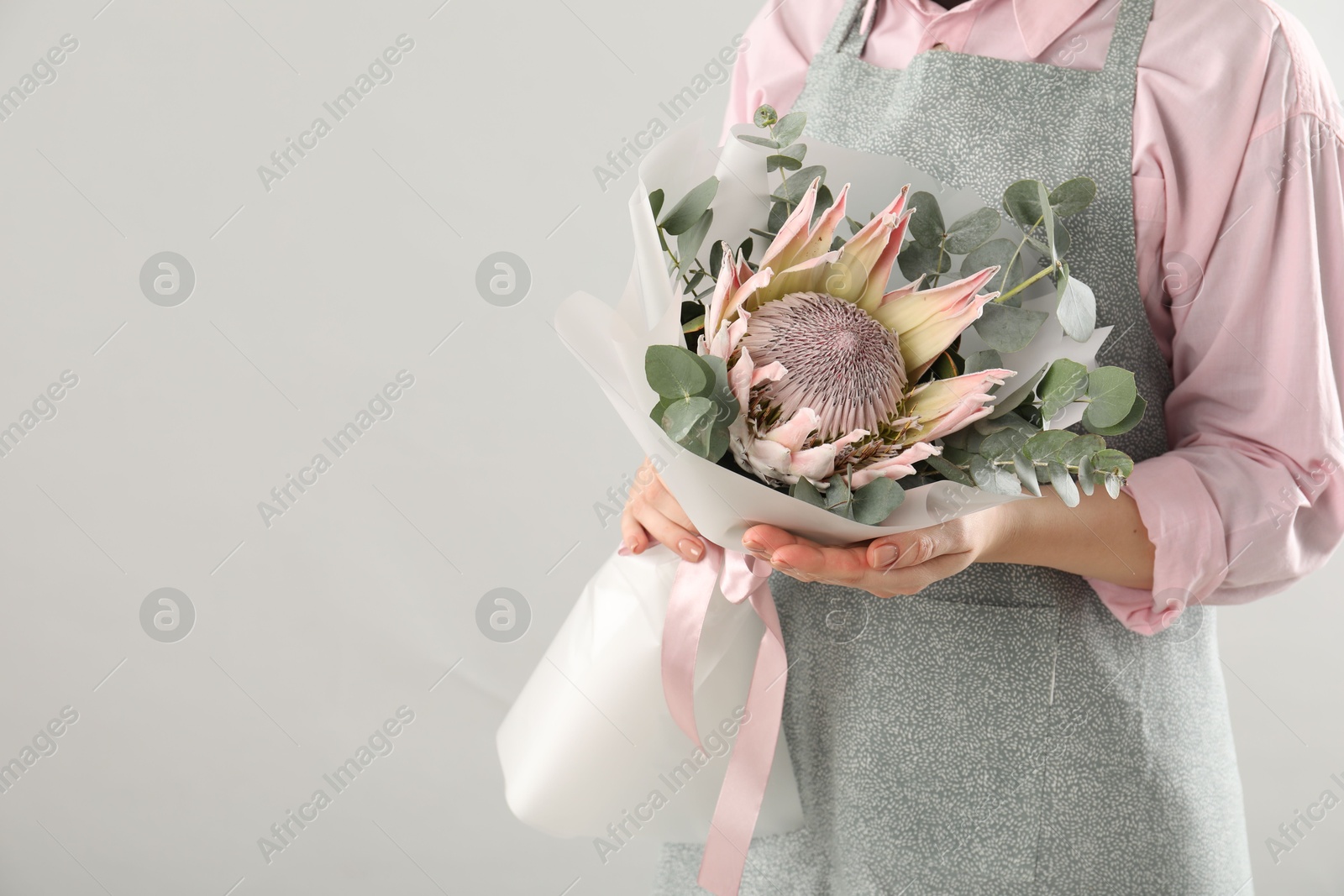 Photo of Florist with beautiful bouquet on light background, closeup. Space for text