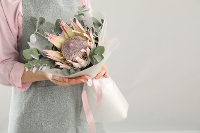 Photo of Florist with beautiful bouquet on light background, closeup. Space for text