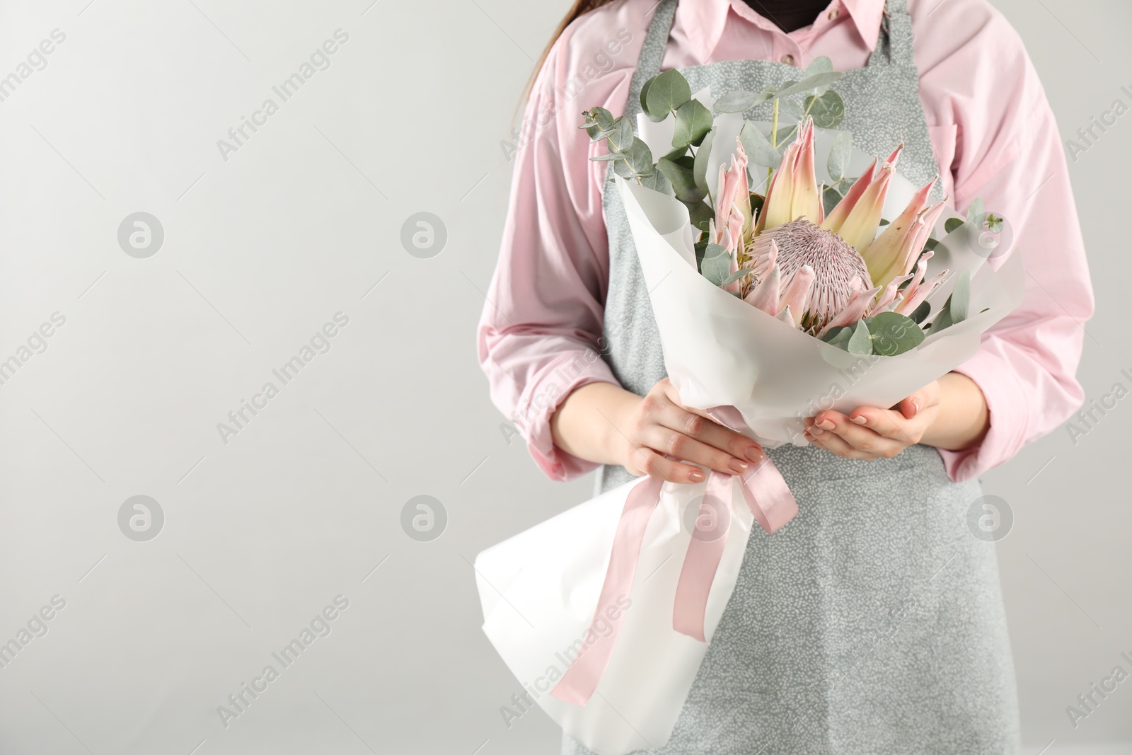 Photo of Florist with beautiful bouquet on light background, closeup. Space for text