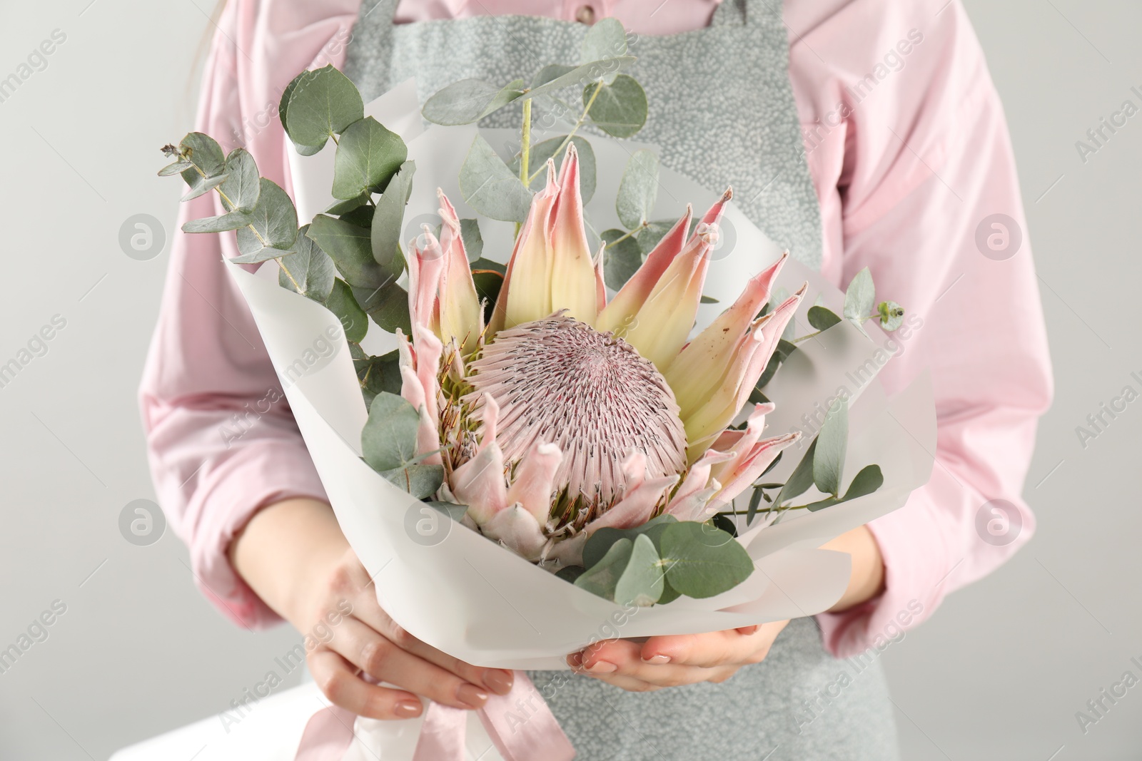 Photo of Florist with beautiful bouquet on light background, closeup