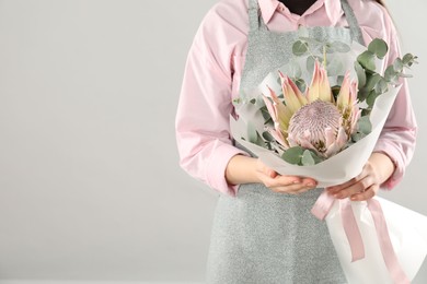 Photo of Florist with beautiful bouquet on light background, closeup. Space for text