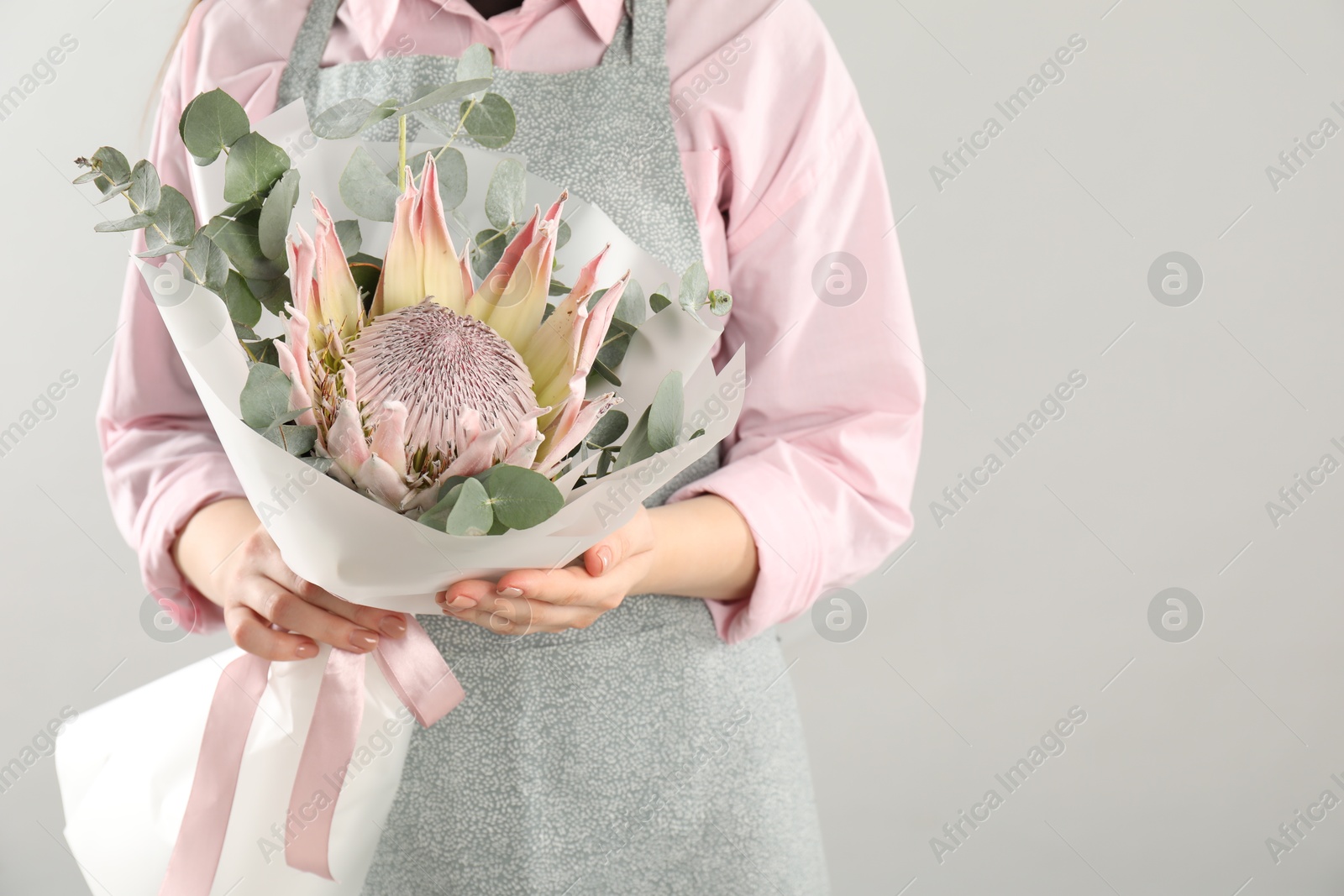 Photo of Florist with beautiful bouquet on light background, closeup. Space for text