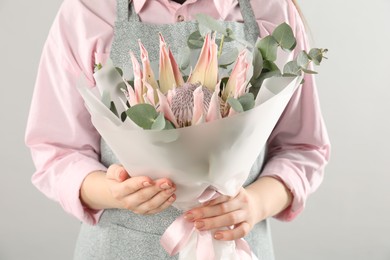 Photo of Florist with beautiful bouquet on light background, closeup