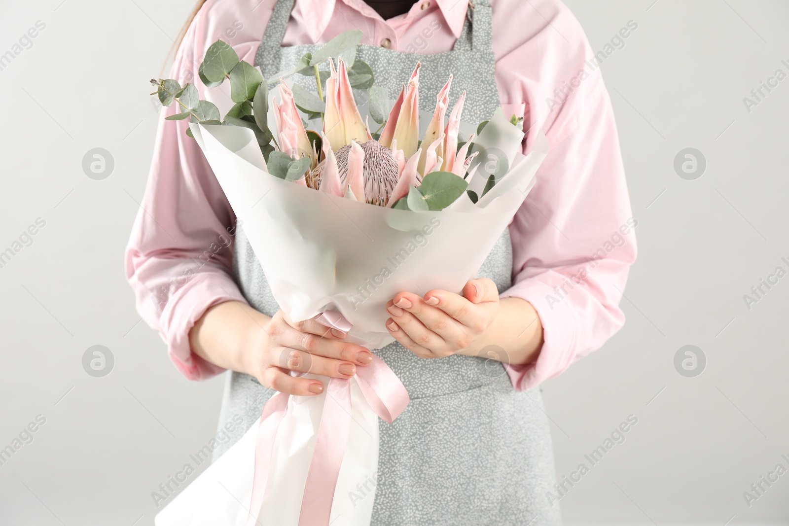 Photo of Florist with beautiful bouquet on light background, closeup