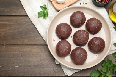 Photo of Many fresh raw meatballs and ingredients on wooden table, flat lay. Space for text