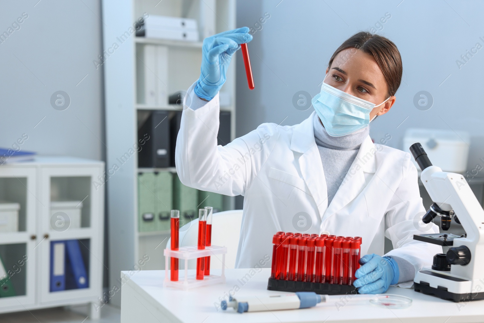 Photo of Laboratory testing. Doctor holding test tube with blood sample at table indoors