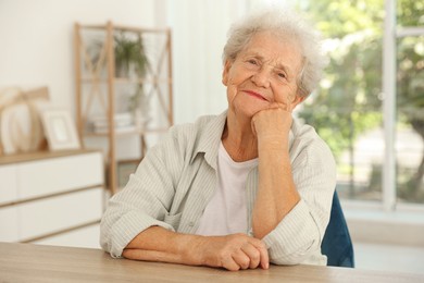 Portrait of beautiful senior woman at wooden table indoors