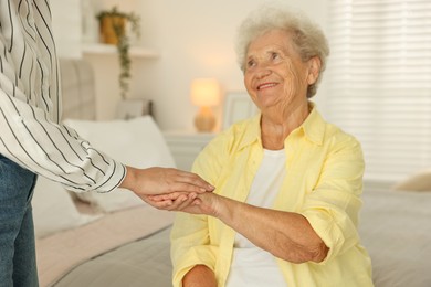 Senior woman holding hands with her granddaughter indoors, selective focus