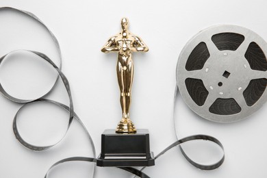 Photo of Golden trophy in shape of human figure and film reel on white background, top view