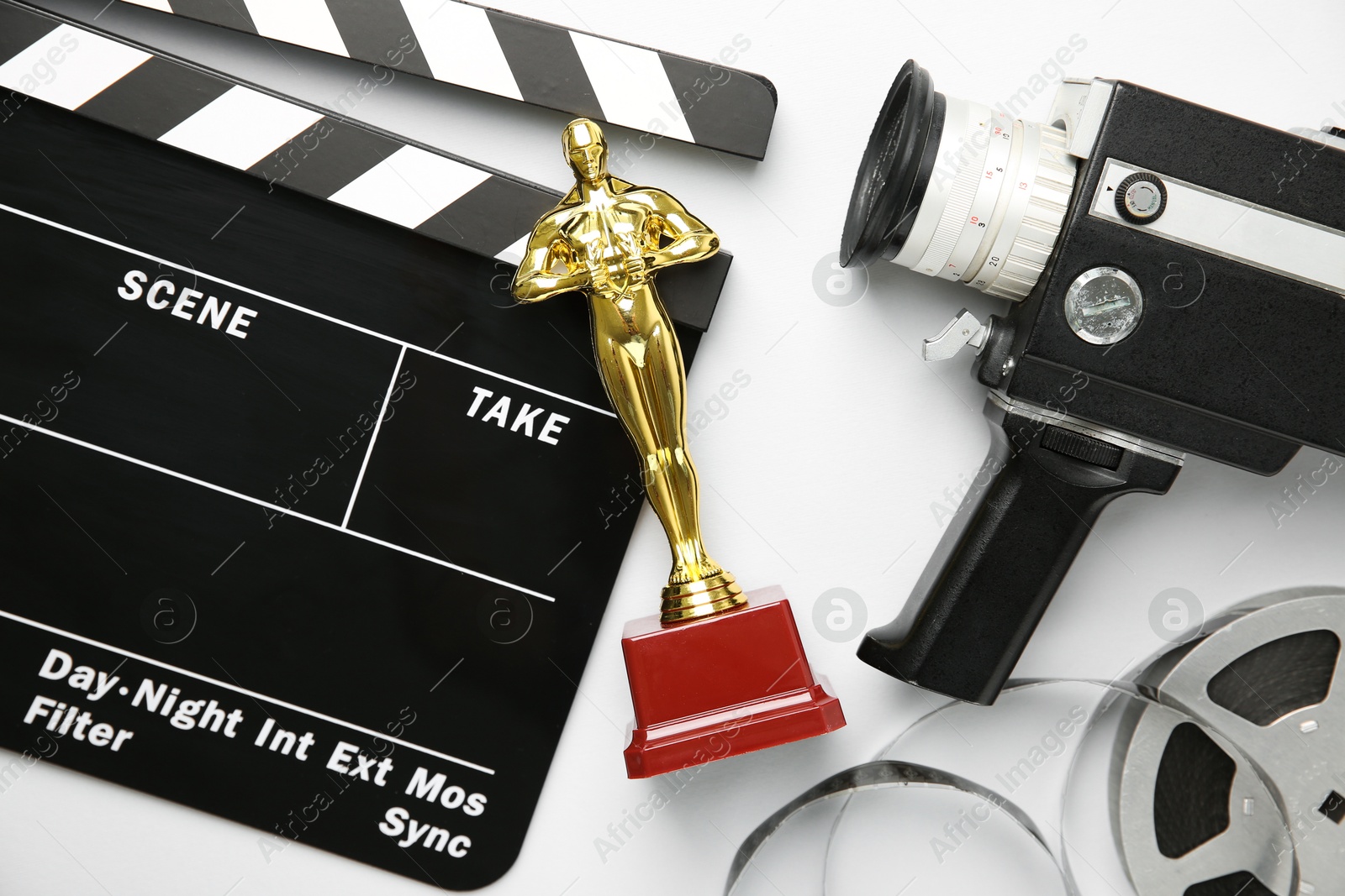 Photo of Golden trophy in shape of human figure, movie clapper, film reel and video camera on white background, top view