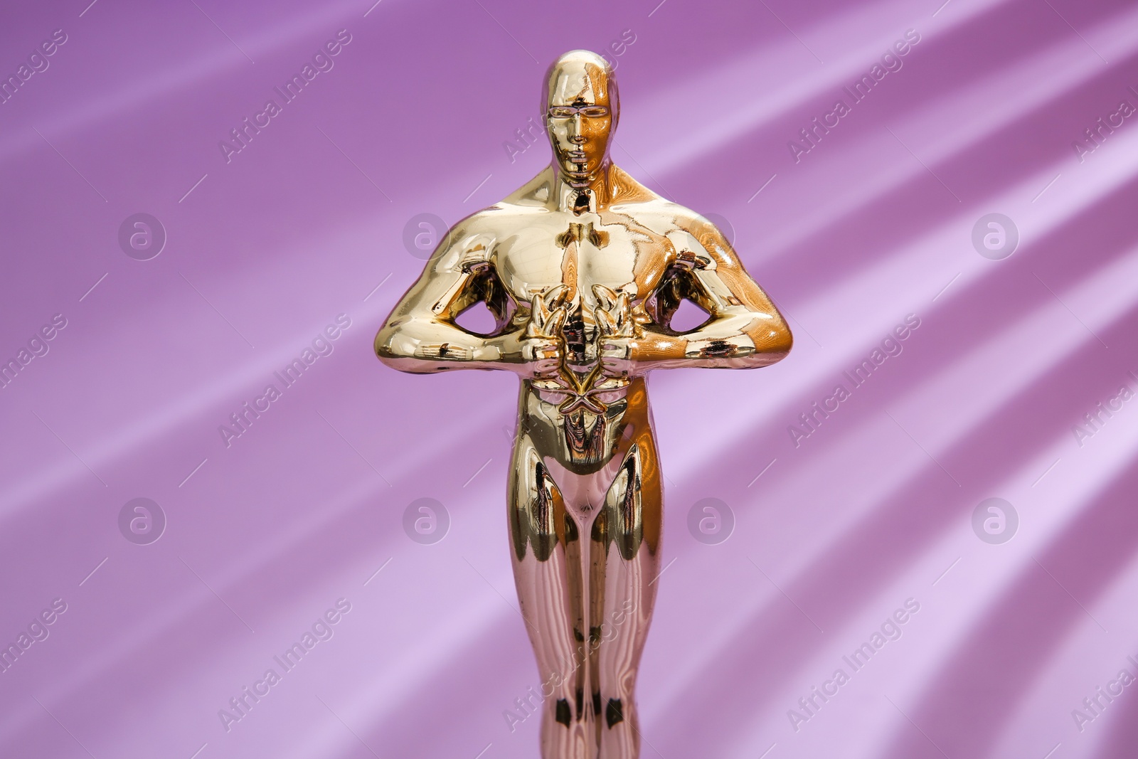 Photo of Golden trophy in shape of human figure on violet background