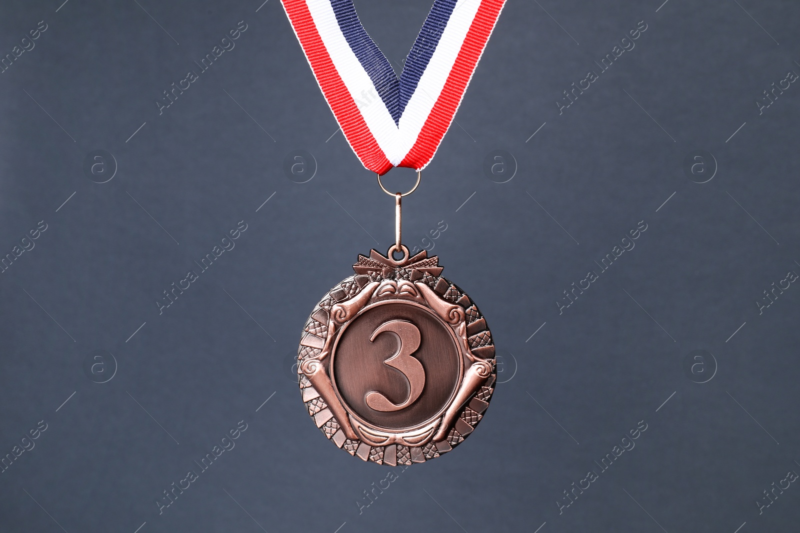 Photo of Bronze medal with striped ribbon on grey background