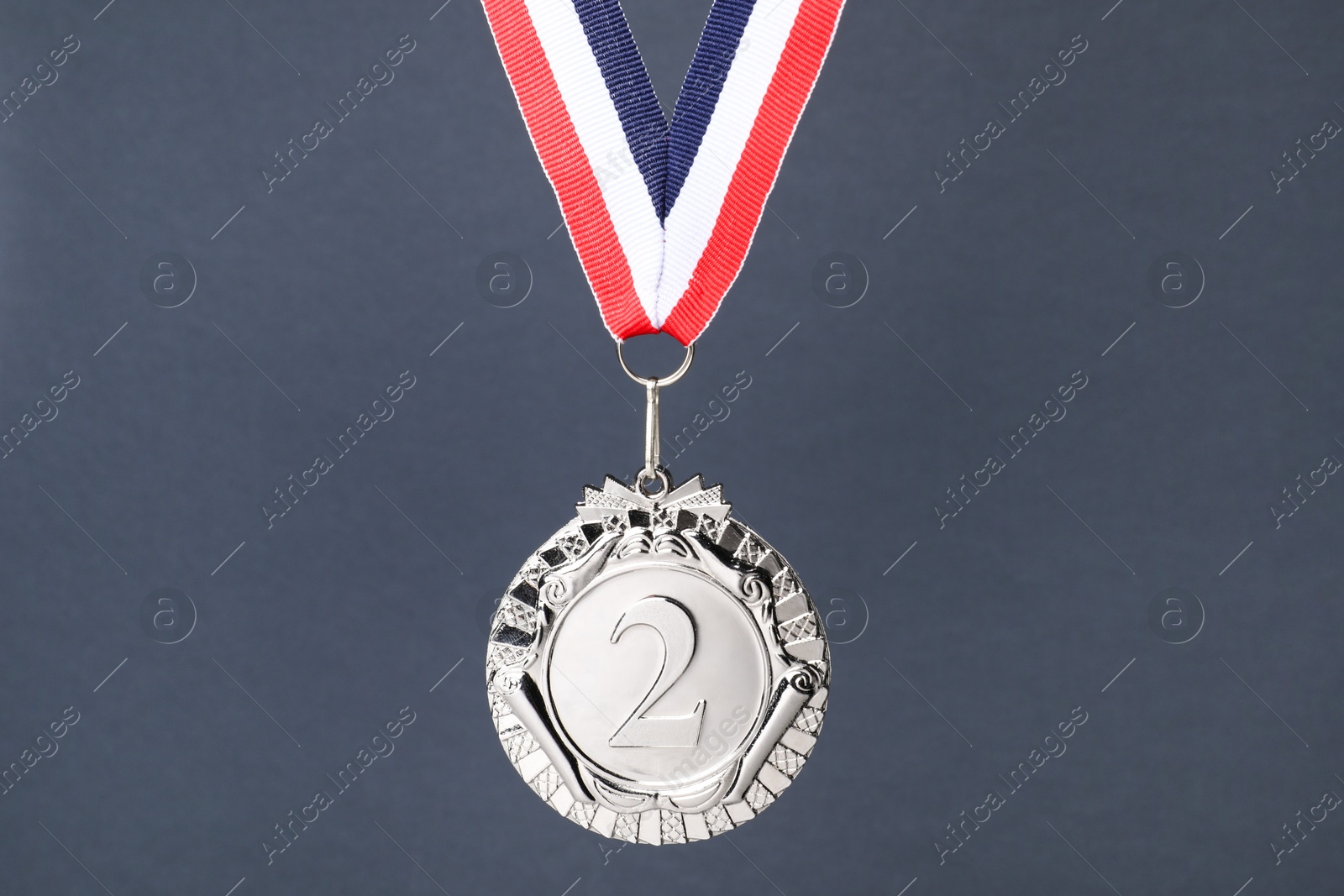 Photo of Silver medal with striped ribbon on grey background