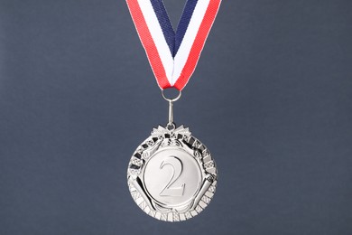 Photo of Silver medal with striped ribbon on grey background