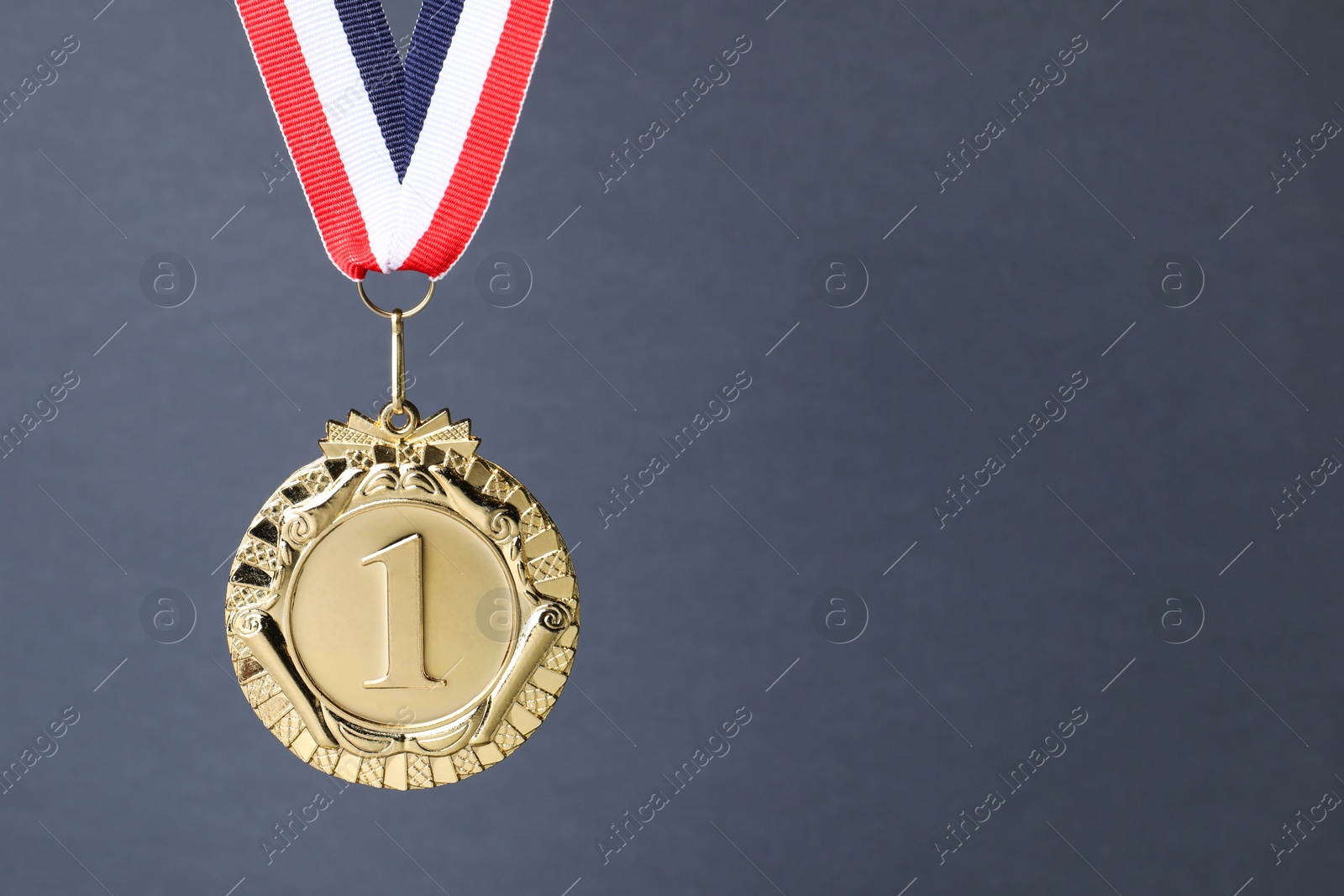 Photo of Golden medal with striped ribbon on grey background, space for text