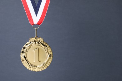 Photo of Golden medal with striped ribbon on grey background, space for text