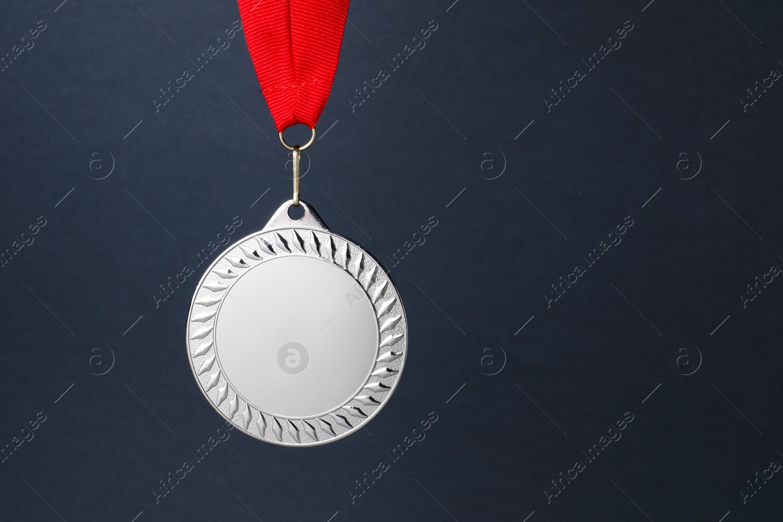 Photo of Silver medal with red ribbon on dark grey background, space for text