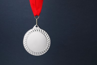 Photo of Silver medal with red ribbon on dark grey background, space for text