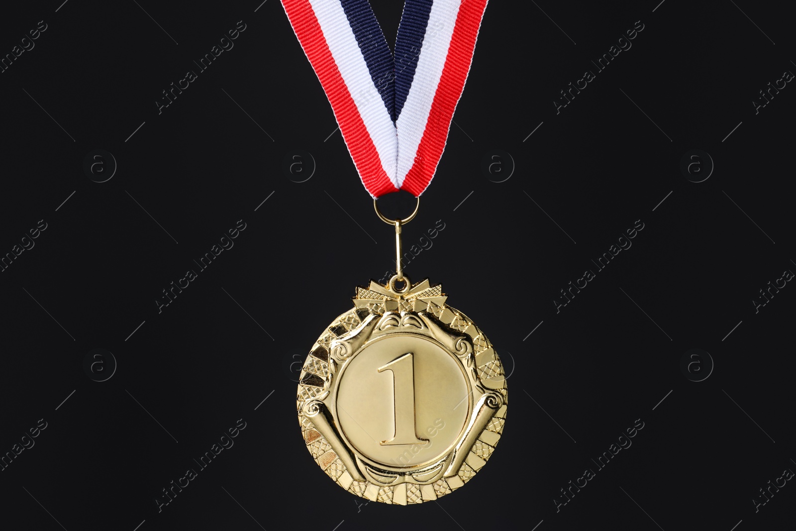 Photo of Golden medal with striped ribbon on black background