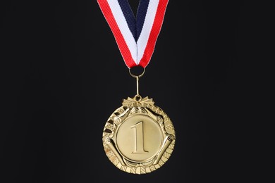 Photo of Golden medal with striped ribbon on black background