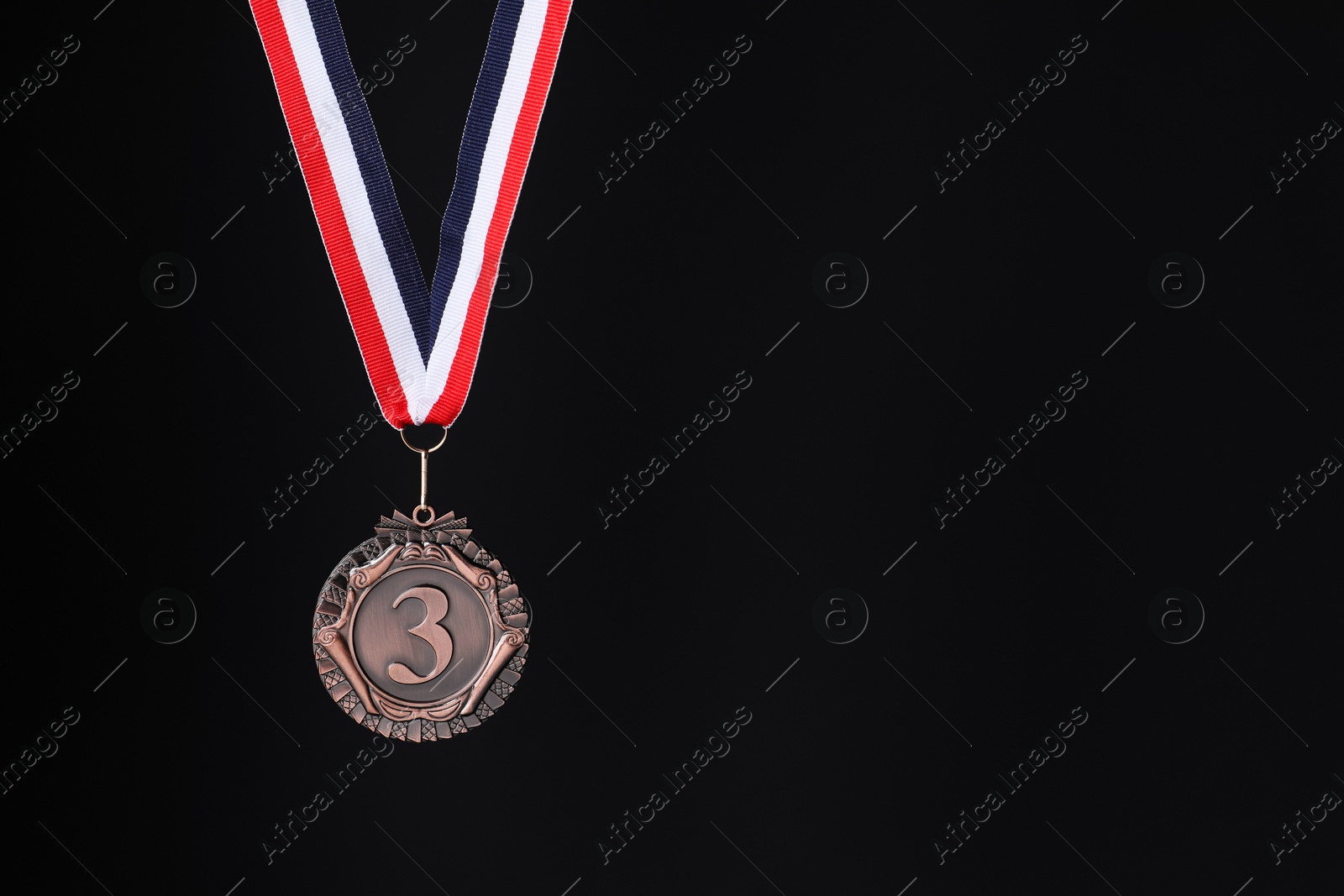 Photo of Bronze medal with striped ribbon on black background, space for text