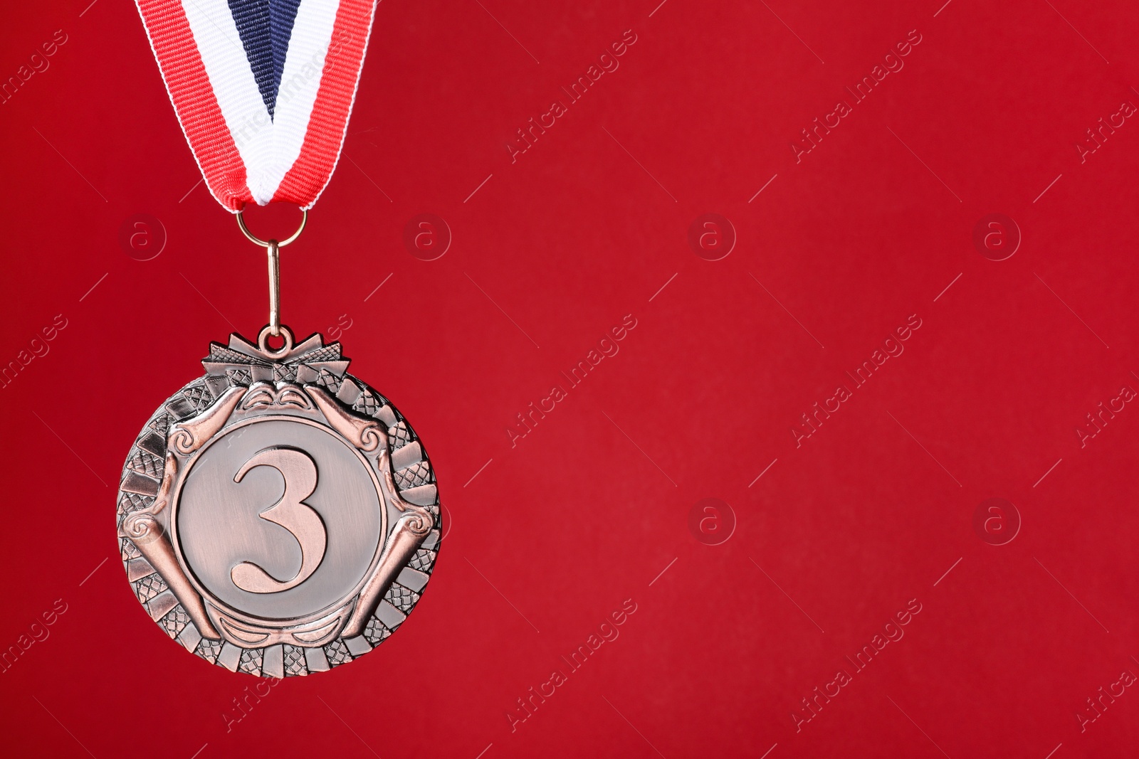 Photo of Bronze medal with striped ribbon on red background, space for text