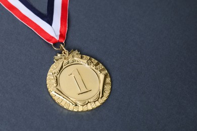 Photo of Golden medal with striped ribbon on grey background, closeup. Space for text