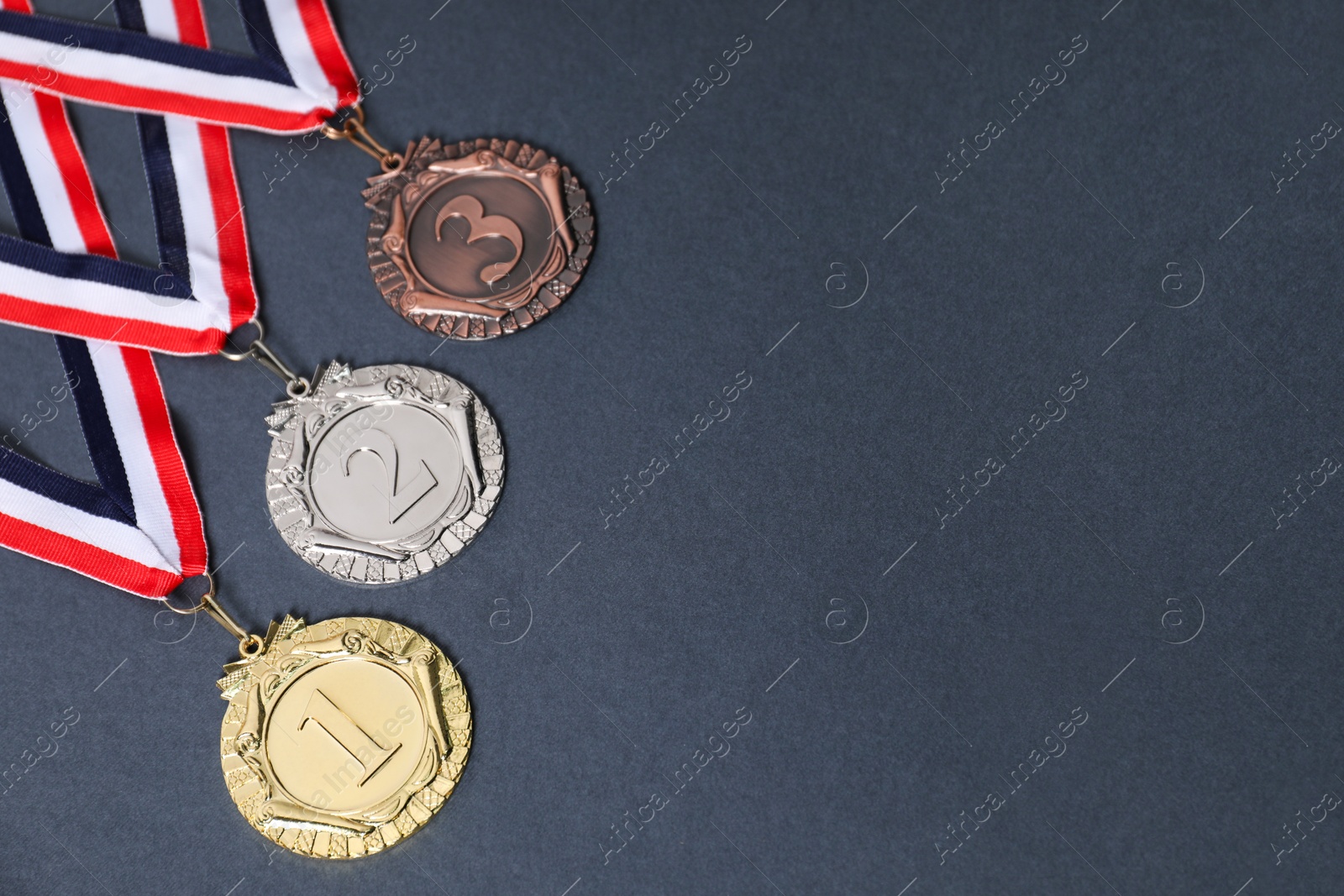 Photo of Golden, silver and bronze medals on grey background, space for text