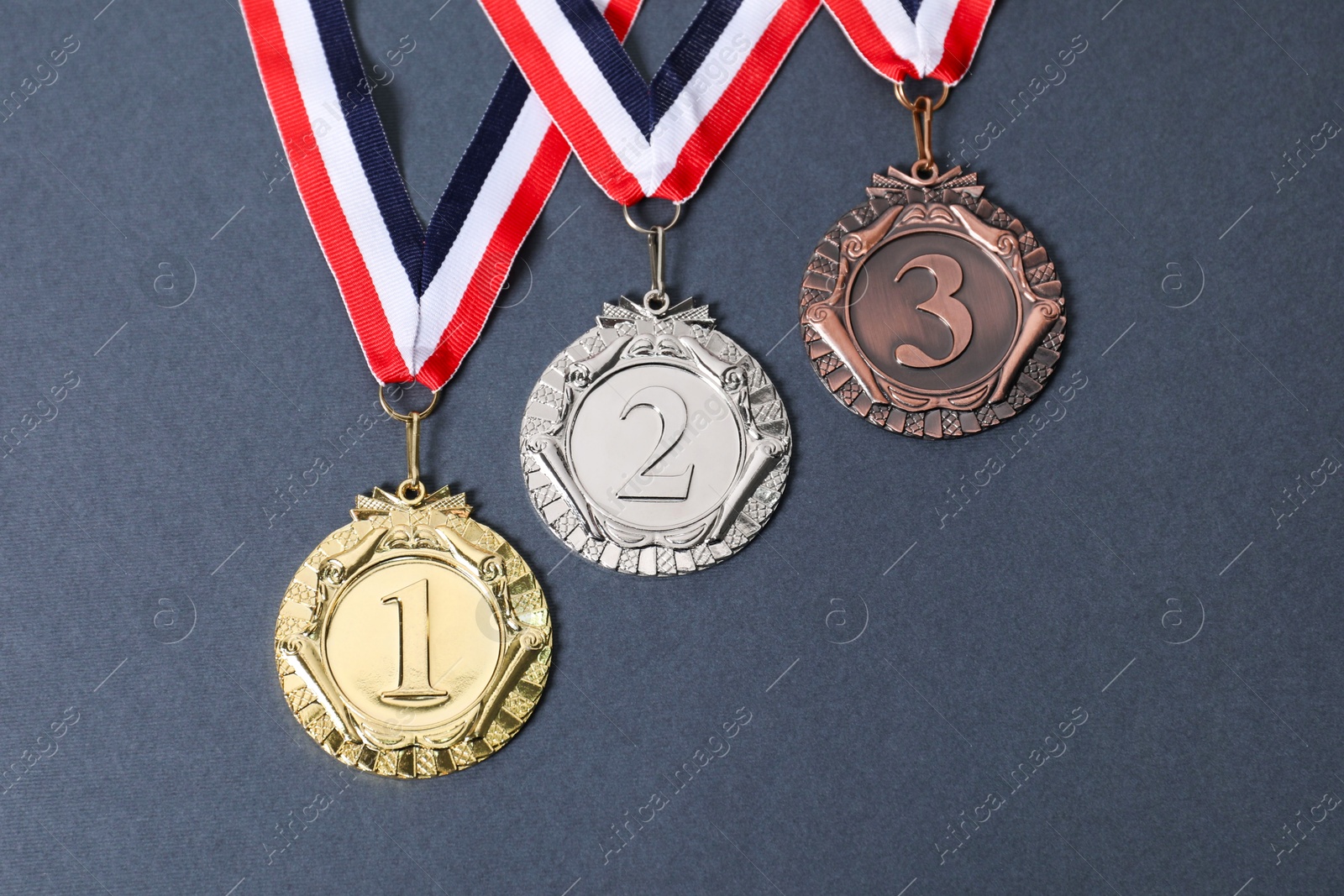 Photo of Golden, silver and bronze medals on grey background, above view